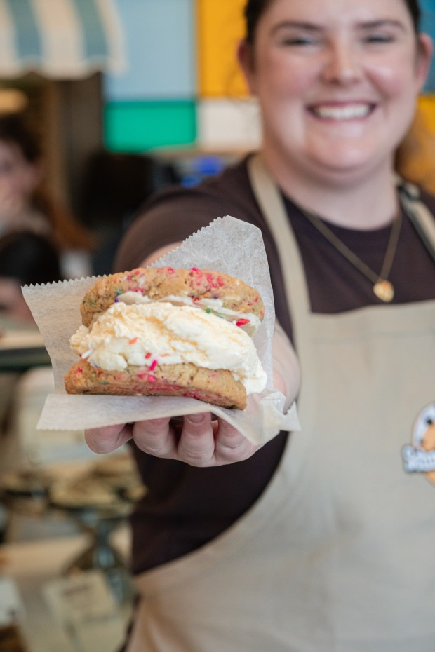 An employee at Schmackary's gourmet cookie store serves up a fresh-scooped ice cream cookie sandwich. The shop opens to the public on Saturday, Feb. 28, at 1255B University Ave., San Diego. (Jeromy Estabillo Chan/Slique Media)
