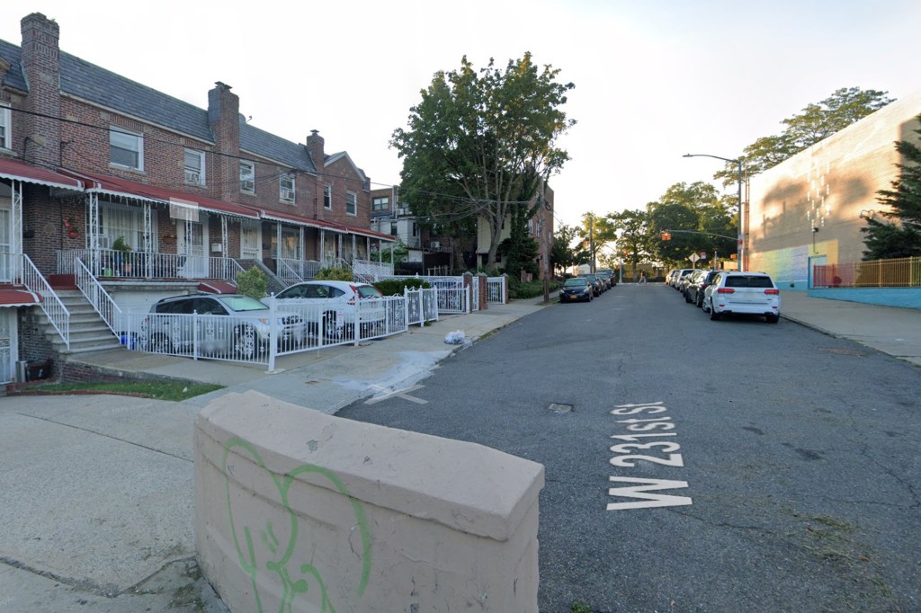 Street view of W. 231st St., with row houses on the left and a building with a mural on the right.