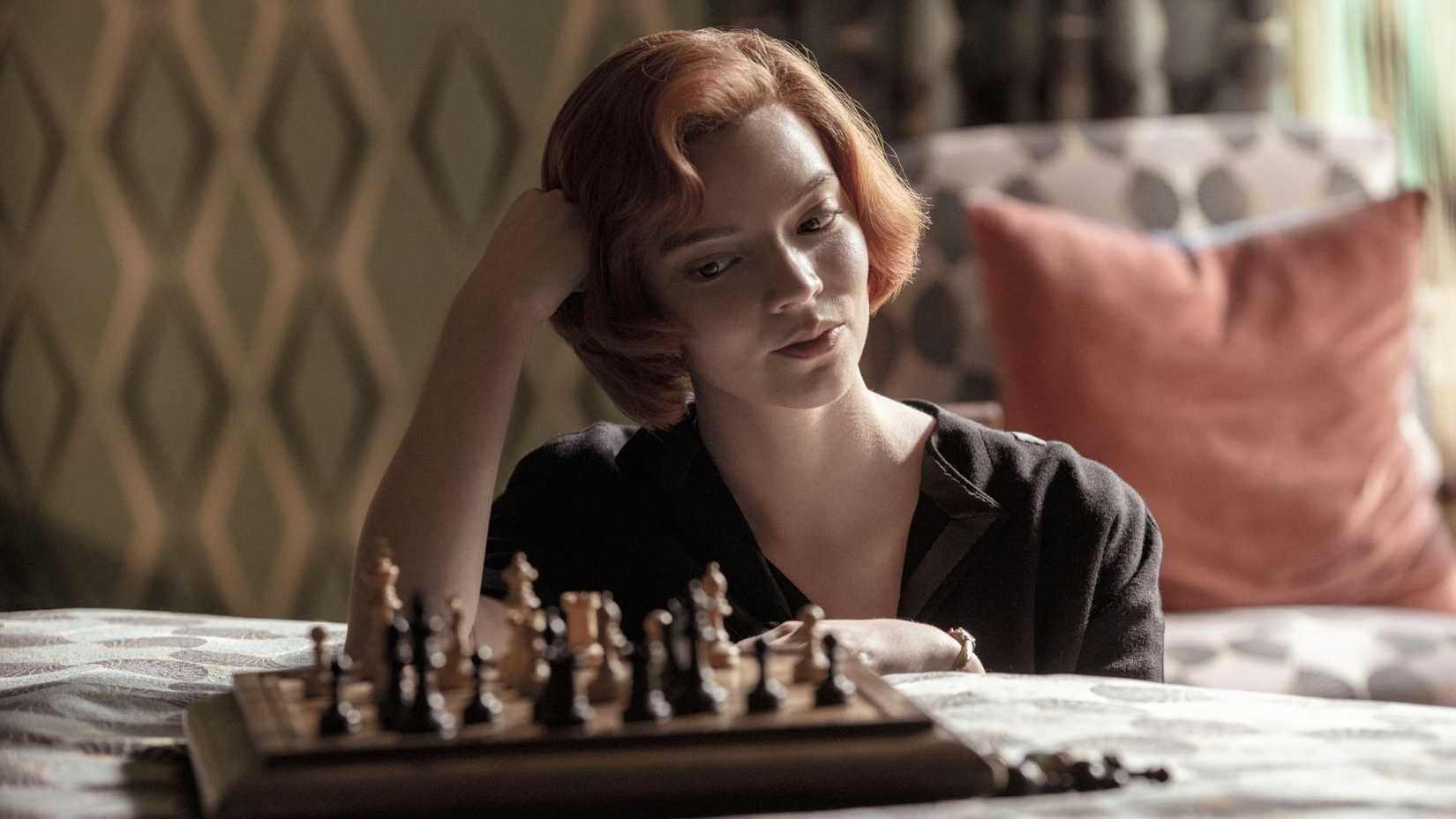 Beth resting her head on her hand and considering her chess set