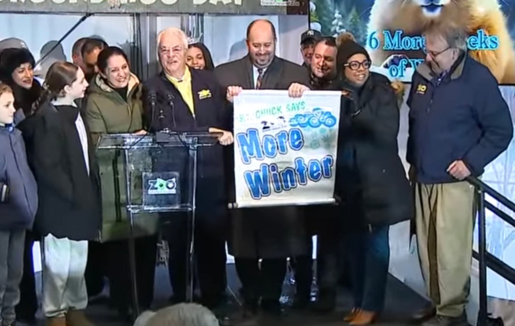 People displaying a banner that reads "S.I. Chuck Says More Winter".
