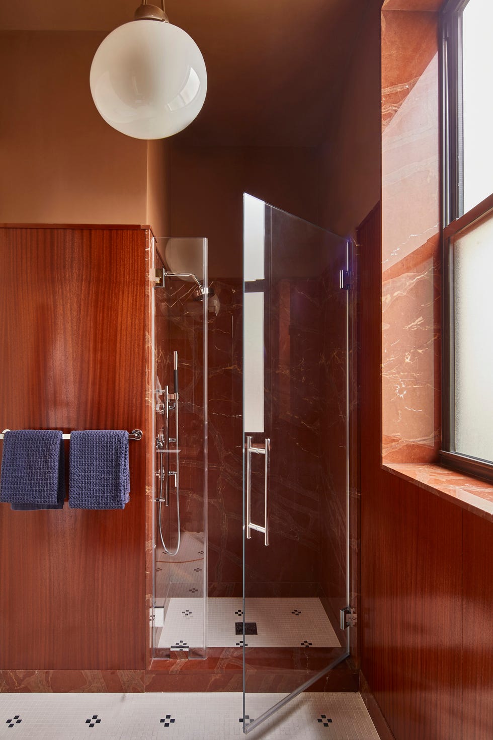 modern shower area featuring glass enclosure, wood paneled walls, and white flooring with black accents