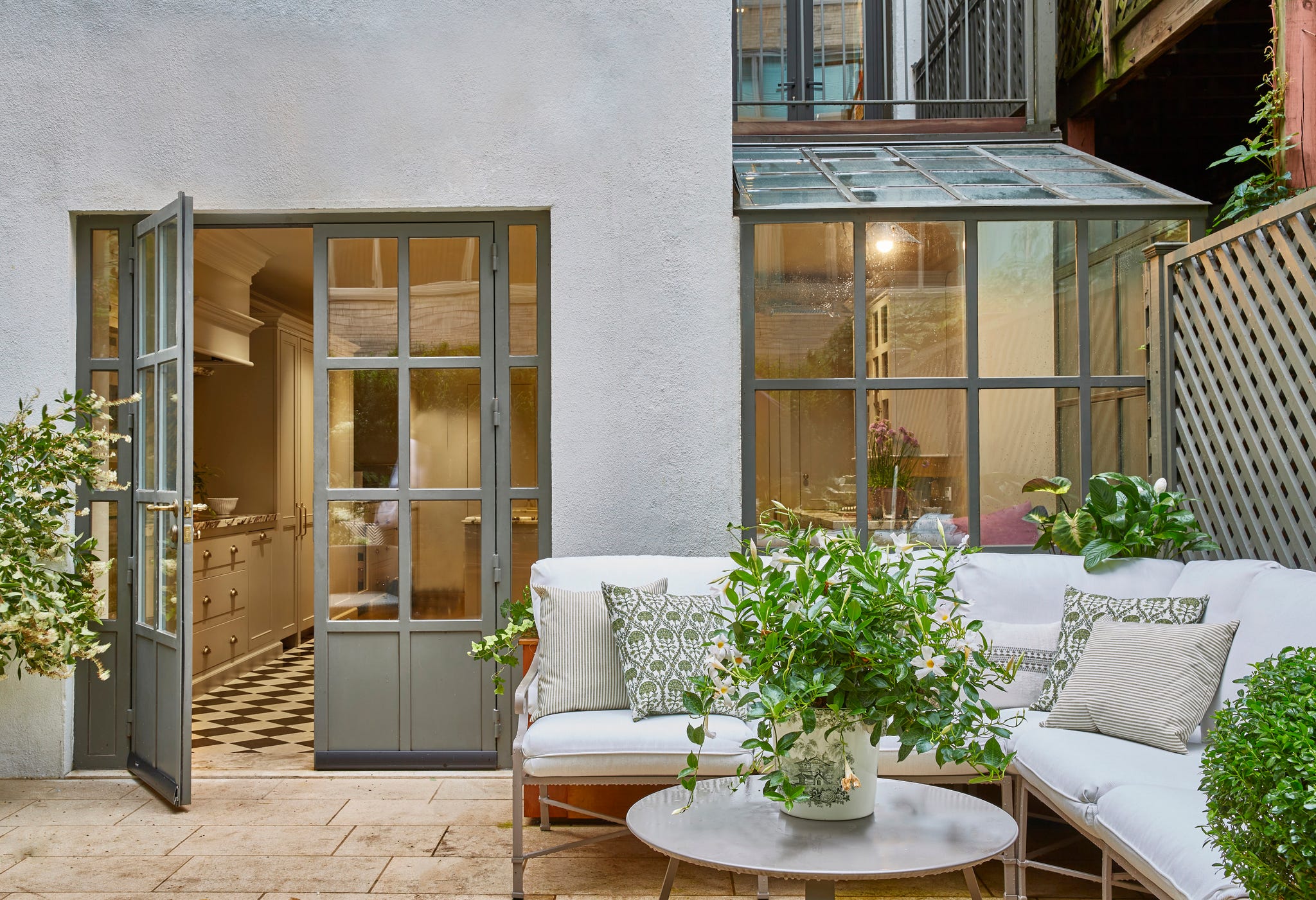 outdoor seating area adjacent to a kitchen with open doors with a white sectional sofa and a round coffee table