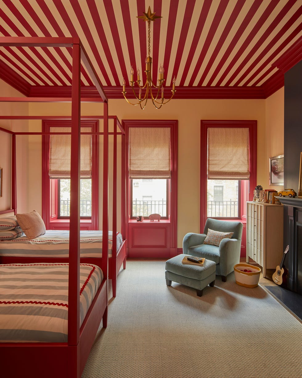 bedroom with two red four poster beds and a red and white striped ceiling