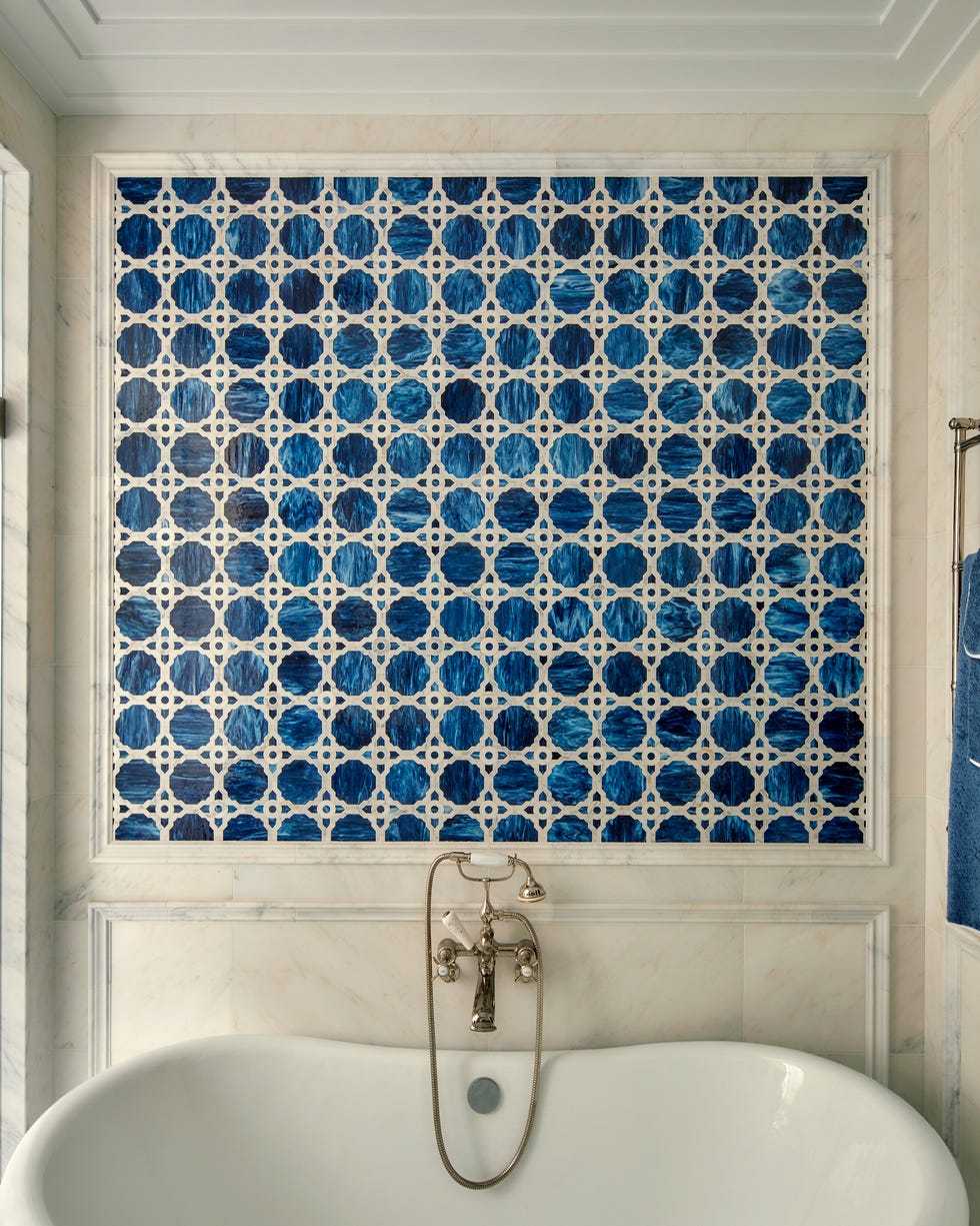white bath tub with section of blue and white tiles on the wall above it