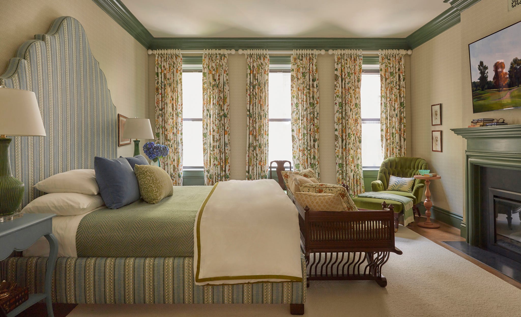 primary bedroom with striped upholstered headboard, patterned curtains, and green painted trim
