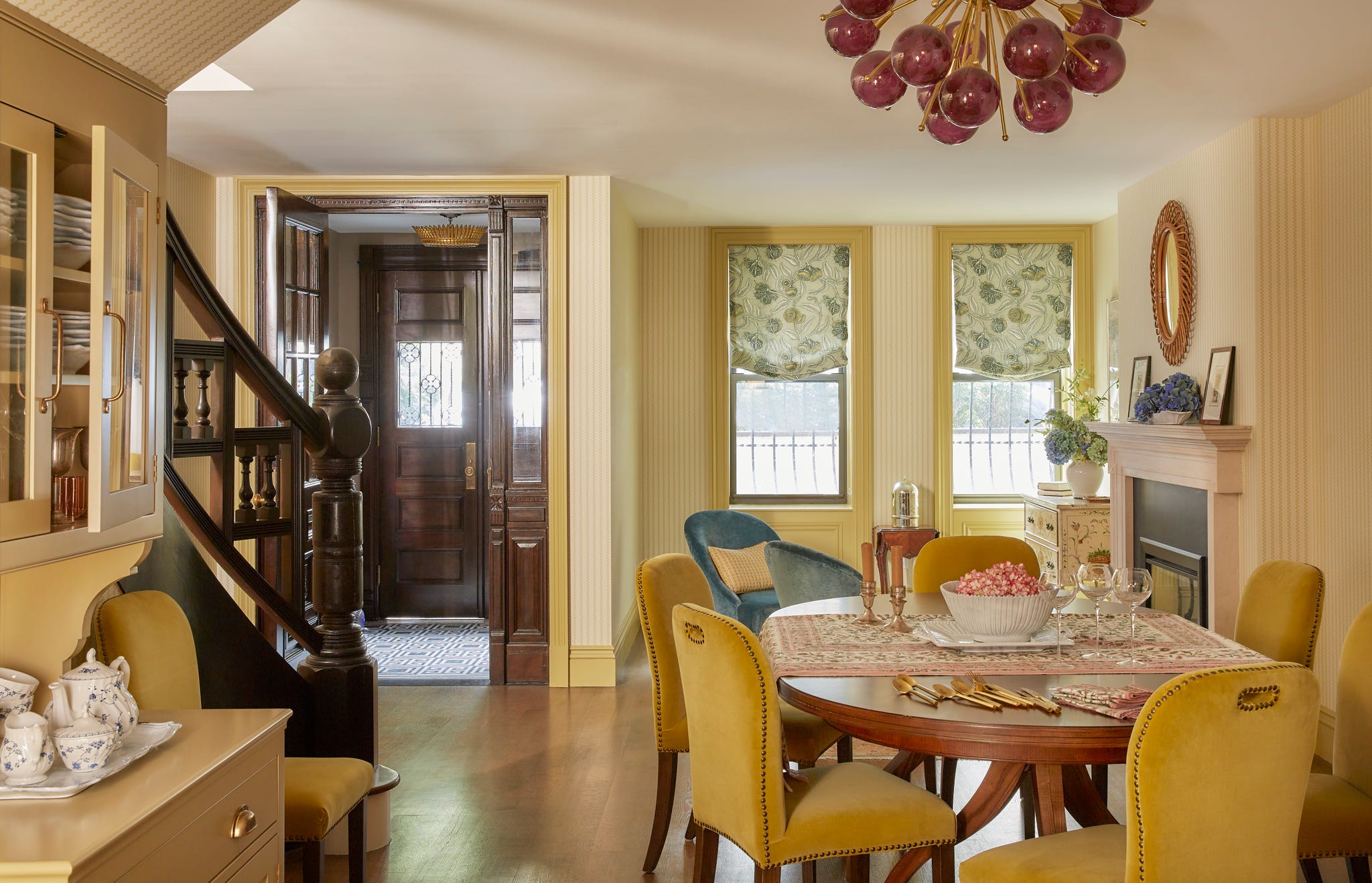 dining area with a wood table and yellow dining chairs and a sitting area with two chairs by a fireplace behind it