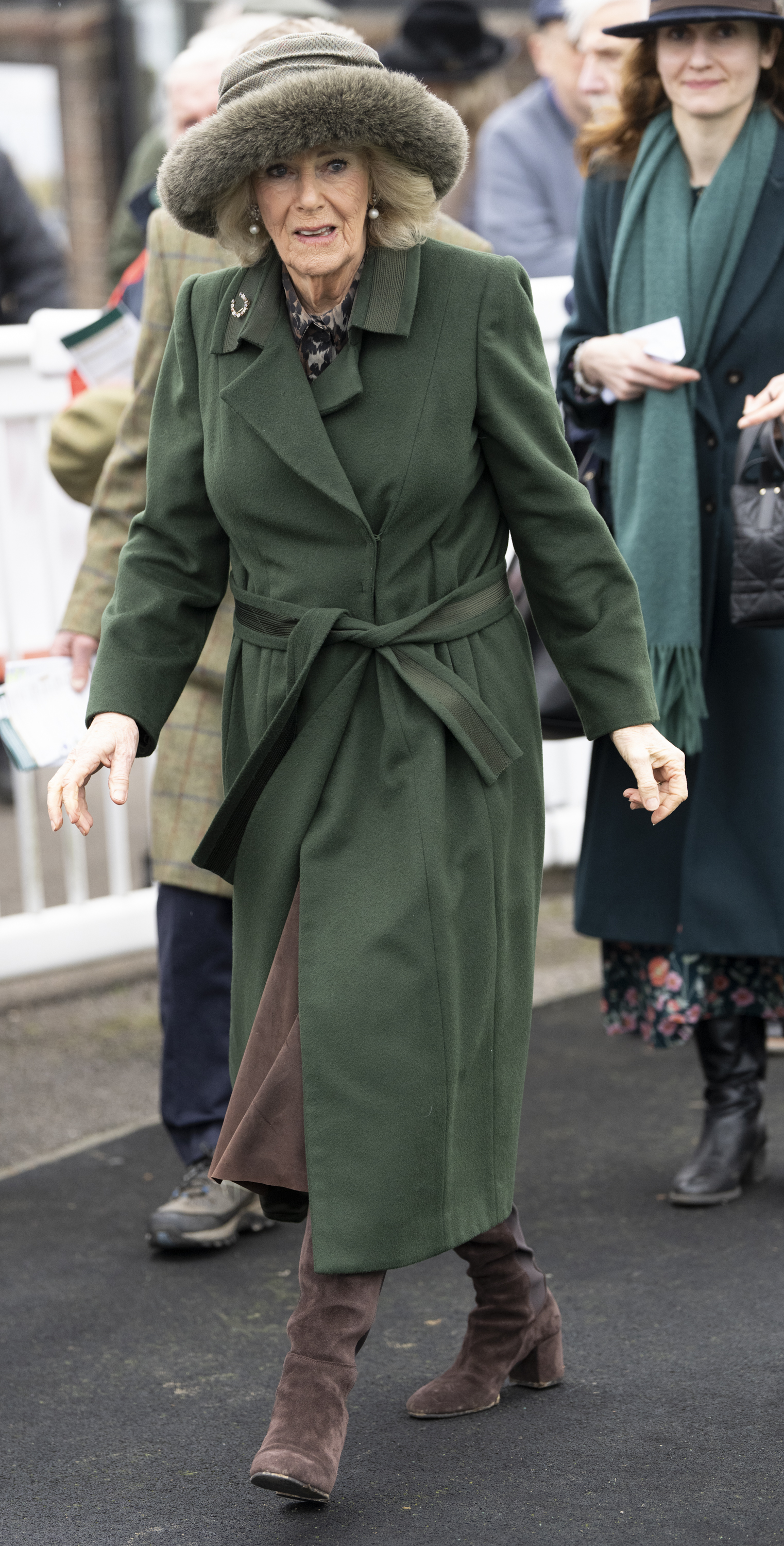 Queen Camilla walking in a green coat and fur hat