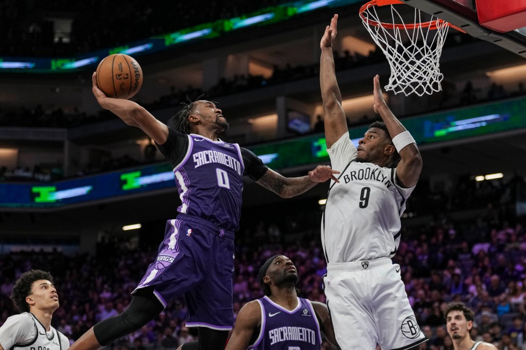 Malik Monk attempts a dunk for the Sacramento Kings while E.J. Liddell of the Brooklyn Nets defends.