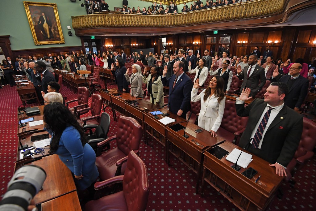 New York City Council members raise their right hands as they take the oath of office.