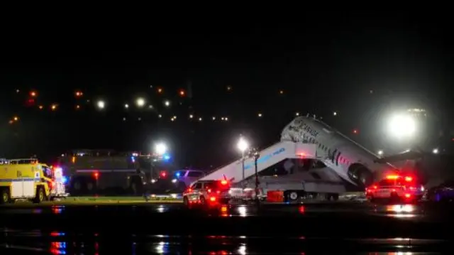 Emergency vehicles are parked near an Air Canada Express jet that had collided with a fire truck at LaGuardia Airport in New York, U.S