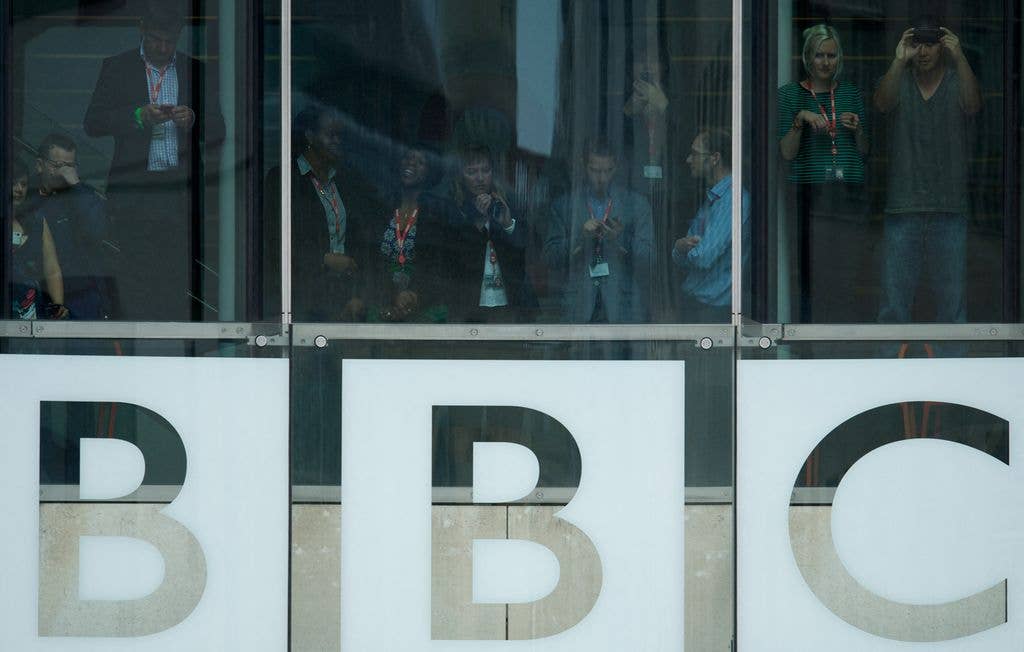 Members of the BBC staff watch from a window before Britain's Queen Elizabeth II leaves after officially opening BBC Broadcasting House 