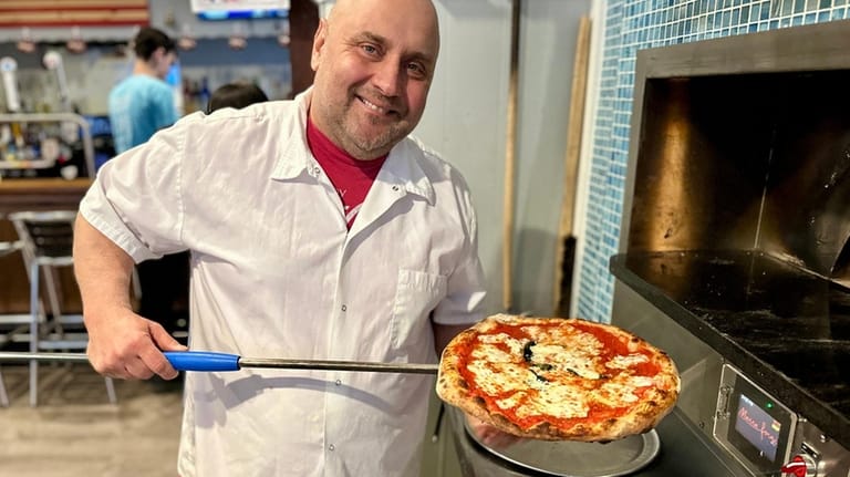 John Zozzaro hefts a Margherita pie at his pizzeria, Zozo's...