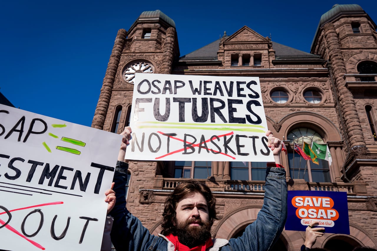 Student holds a sign at an OSAP rally in front of Queen's Park. 