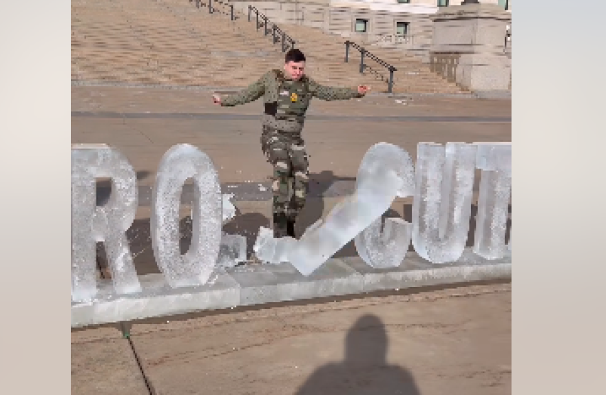 Jake Lang knocks over letters in an ice sculpture outside the Minnesota state Capitol on Feb. 5, 2026. The sculpture said Prosecute ICE. Lang turned it into Pro Ice.