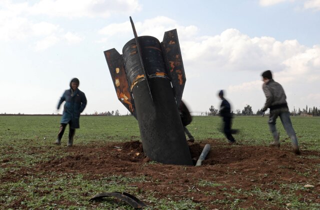 TOPSHOT - Children play around an unexploded missile that landed in an open field on the outskirts of Qamishli, eastern Syria, on March 5, 2026. Gulf countries have been targeted by repeated waves of Iranian drone and missile attacks in retaliation for the massive US-Israeli air campaign. (Photo by Delil SOULEIMAN / AFP via Getty Images)