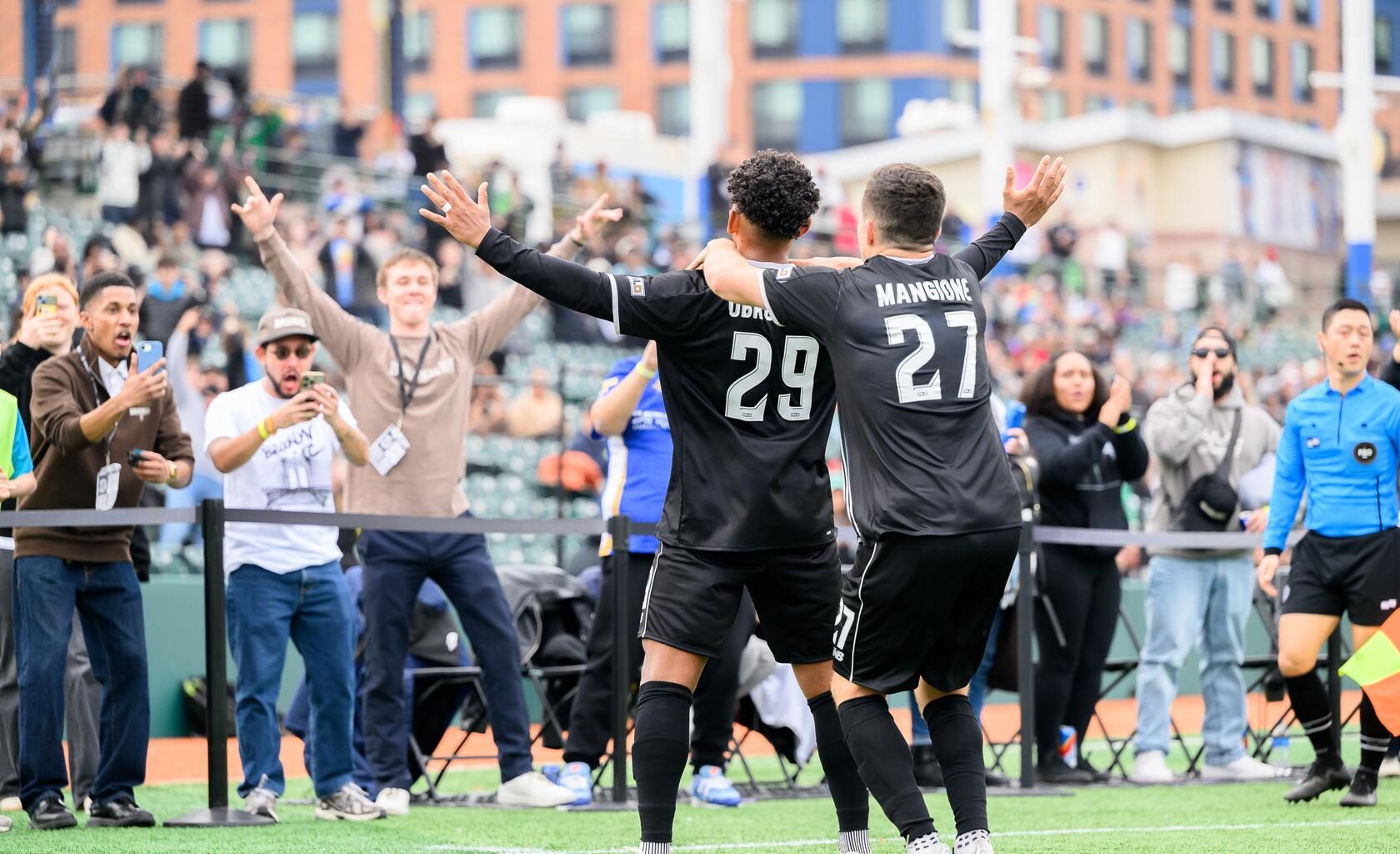 Brooklyn FC men players Juan Carlos Obregón Jr. and Peter Mangione celebrate with supporters after a goal at Maimonides Park.