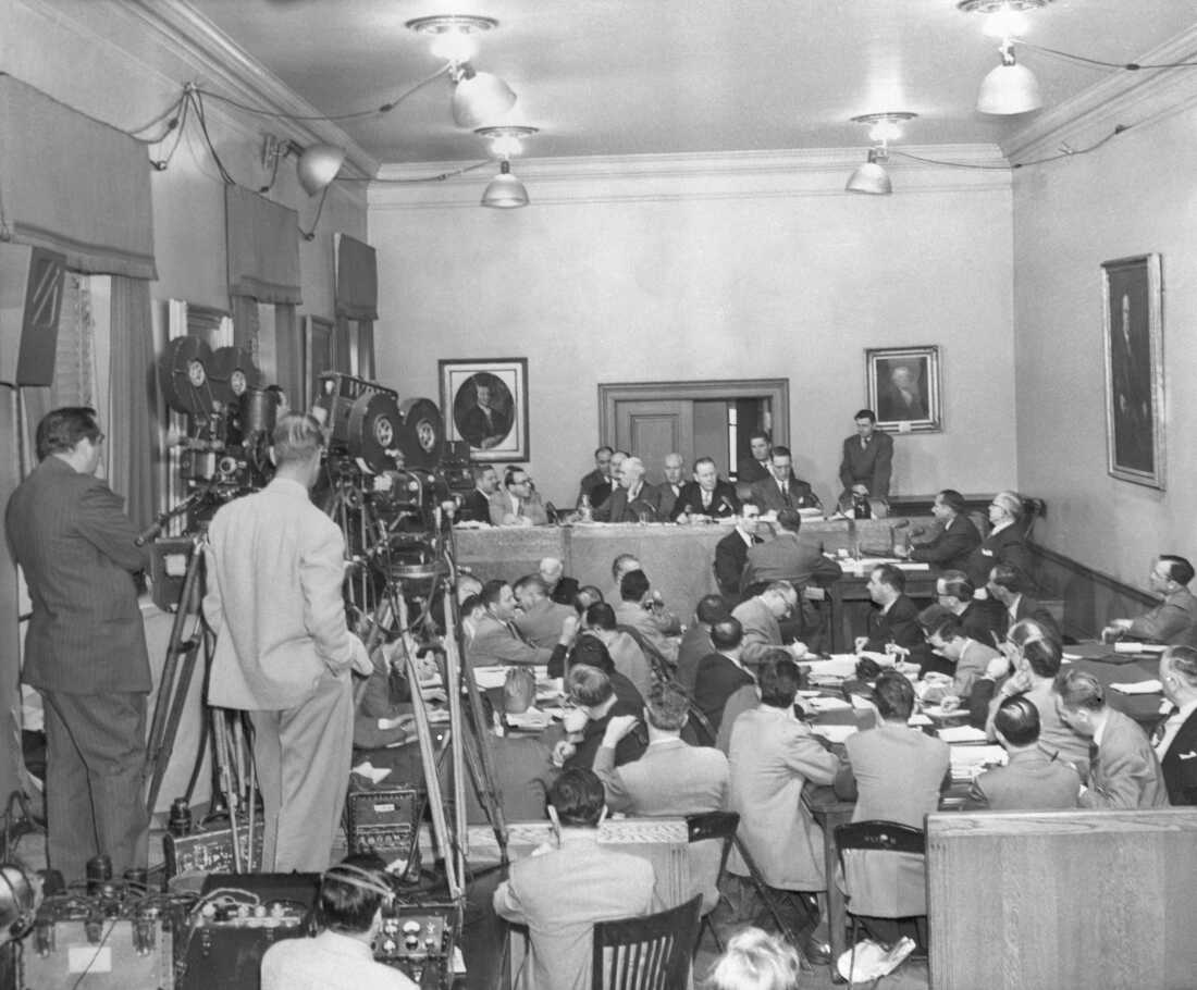 Though television cameras were grinding, star witness Frank Costello (at witness table, right background, leaning forward) was not visible to TV audiences as he testified before the Senate Crime Investigating Committee. Next to Costello is his lawyer, George Wolf. At the committee table are (left to right): Rudolph Halley, chief counsel for the committee; Sen. Charles Tobey (R-N.H.); Sen. Herbert O'Conor; and Sen. Estes Kefauver, committee chairman. Costello objected to TV.