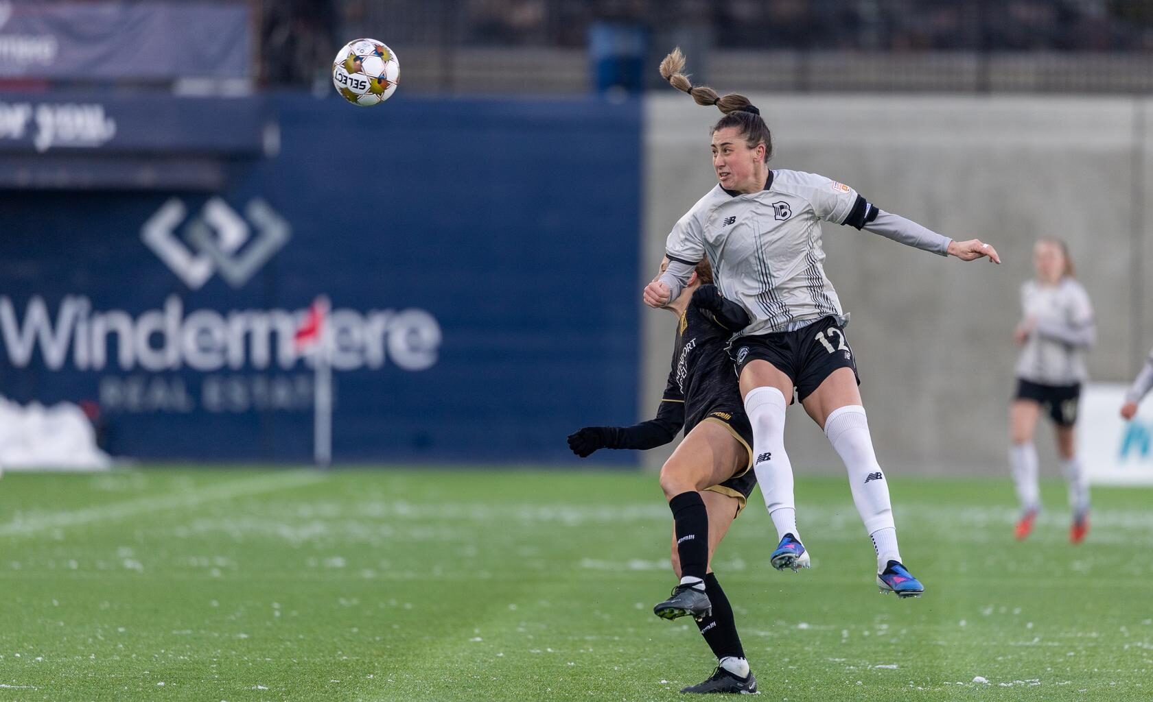 Brooklyn FC defender Hope Breslin heads the ball while contesting an aerial challenge against an opponent during a match.
