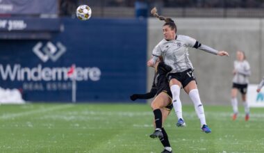 Brooklyn FC defender Hope Breslin heads the ball while contesting an aerial challenge against an opponent during a match.