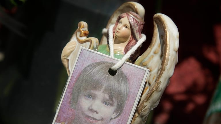 A photograph of Etan Patz hangs on an angel figurine,...