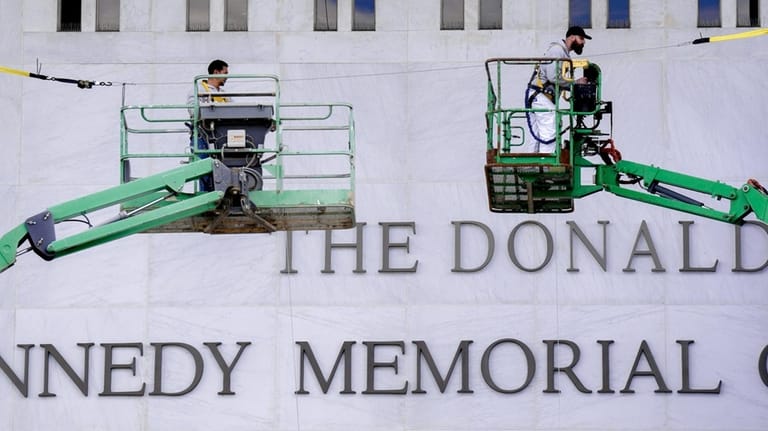 Workers affix signage adding President Donald Trump's name on the...