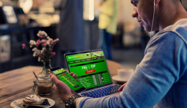 Man using online sports betting services on phone and laptop