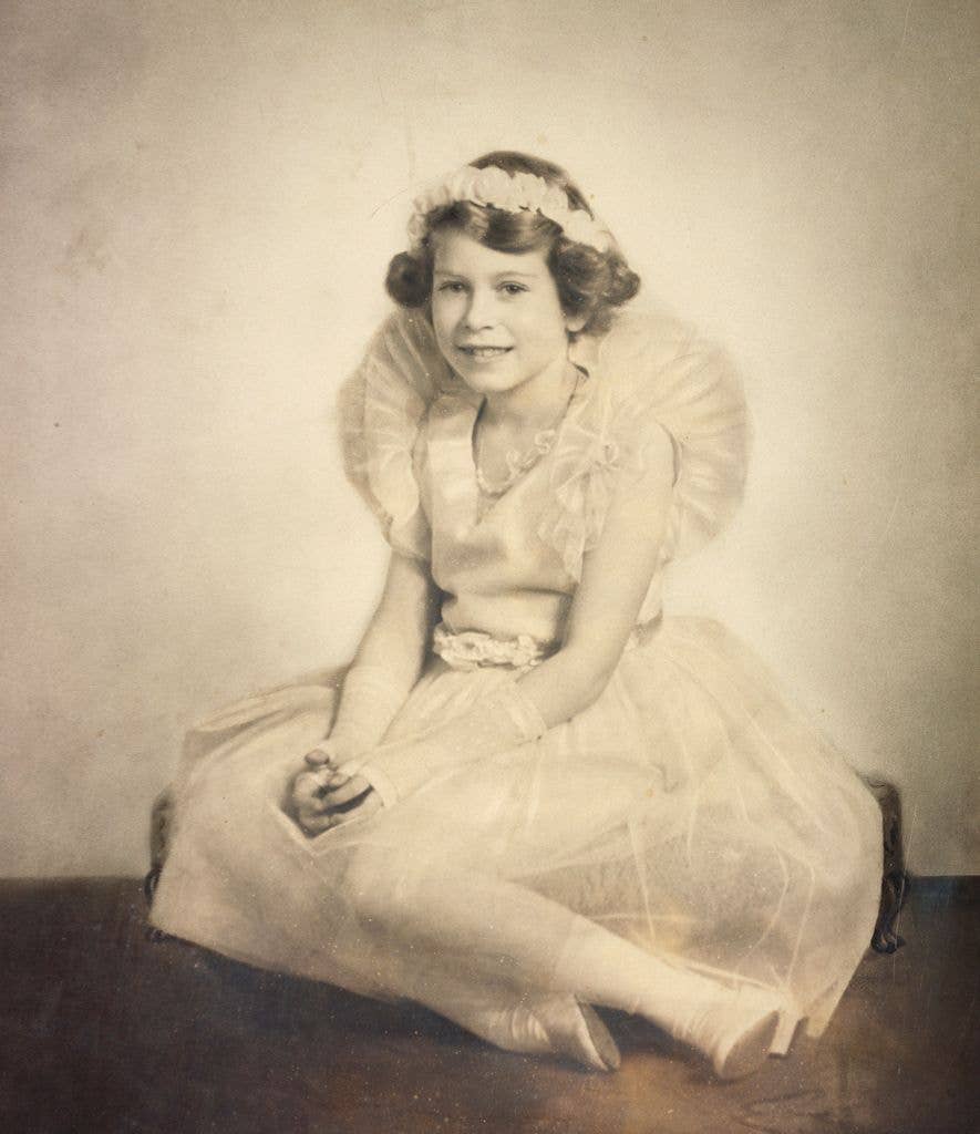 A young Princess Elizabeth sits while wearing her frilled bridesmaid dress for the wedding of her uncle Prince George, Duke of Kent to Princess Marina of Greece and Denmark in November 1934