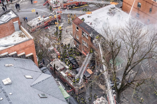 Firefighters battle a four-alarm fire on College Point Boulevard in Queens on Monday.