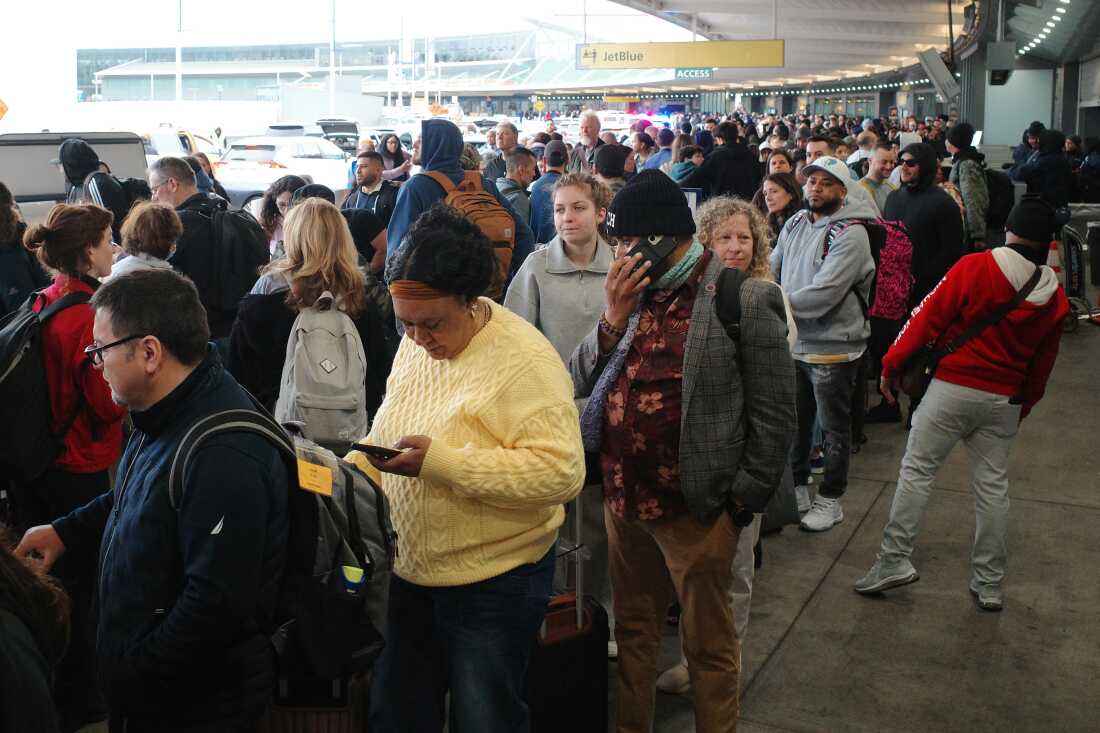 Travelers wait in line to go through TSA screening in Terminal 5 at John F. Kennedy International Airport on Friday in New York. The partial government shutdown has brought the longest TSA wait times in history, forcing some airline customers to rebook flights missed due to airport delays.