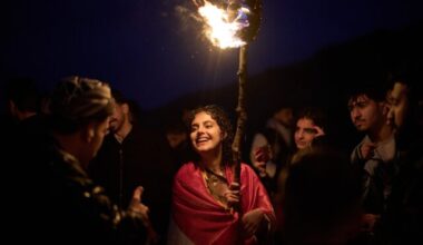 A Kurdish woman in traditional dress holds a lit torch during Nowruz, the Persian New Year, on a hill overlooking the town of Akra in the autonomous Kurdistan Region of Iraq, Friday, March 20, 2026. (AP Photo/Leo Correa)