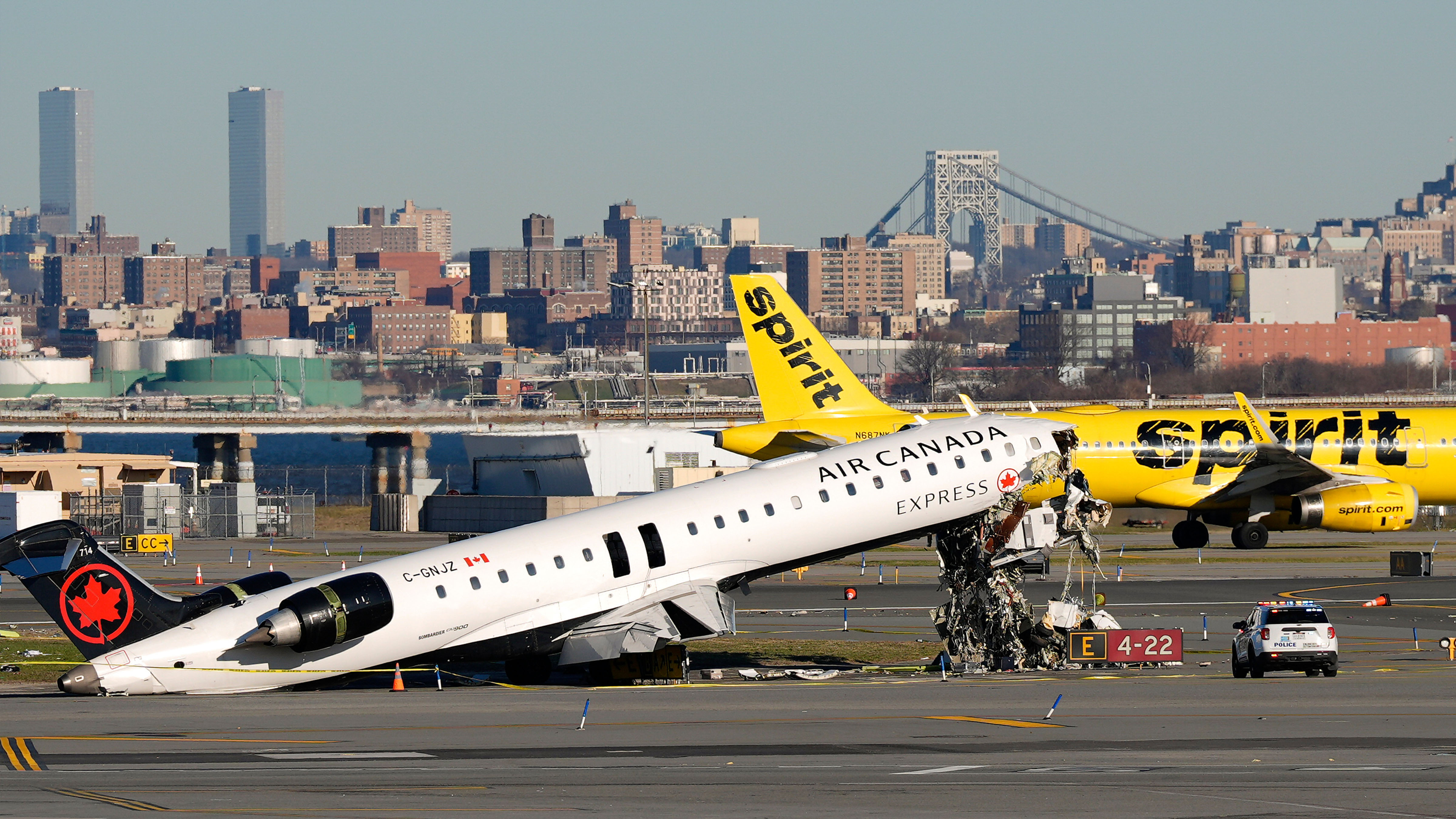 A Spirit Airlines jet taxis past an Air Canada Express jet sitting on the side of a runway, Tuesday, March 24, 2026, where it had collided with a Port Authority fire truck Sunday night at LaGuardia Airport in New York. 