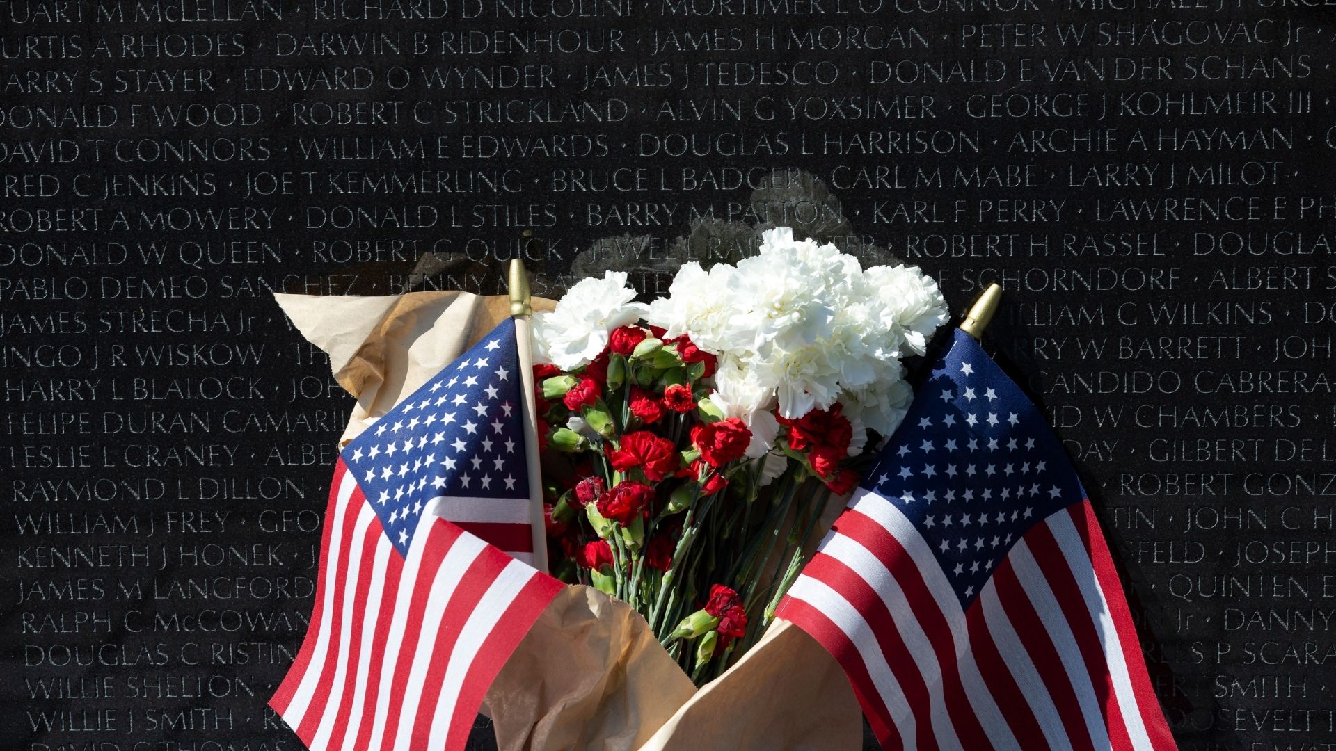 Flowers with American flags are left at the Vietnam Veterans Memorial on the National Mall on Memorial Day in Washington, Monday, May 25, 2020.