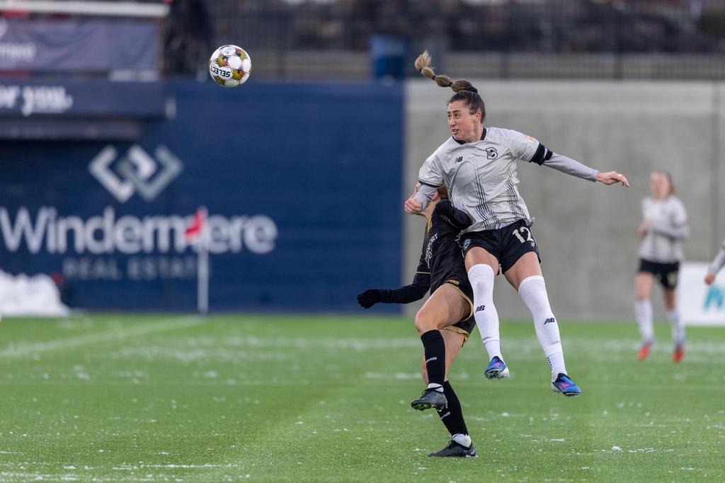 Brooklyn FC defender Hope Breslin heads the ball while contesting an aerial challenge against an opponent during a match.