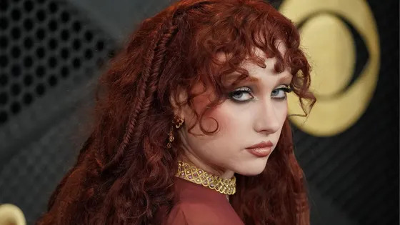 A woman with red hair looks at the camera.