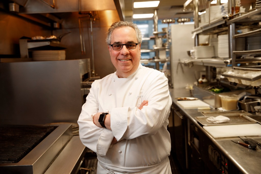 Chef Michael Lomonaco in a kitchen with his arms crossed.