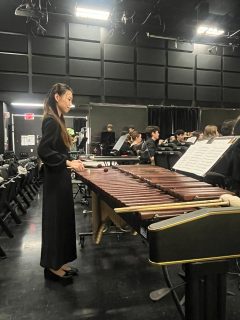 Wind Ensemble student standing in front of instrument