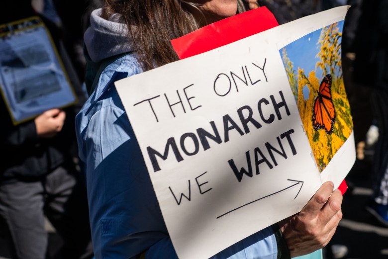 A protestor holds a sign while marching in the No Kings Day event in Manhattan on Saturday, March 28, 2026. Photo by Allison Hunter for The Haitian Times.
