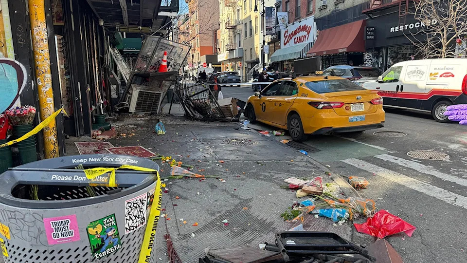 Yellow taxi sits amid debris after Manhattan sidewalk crash.