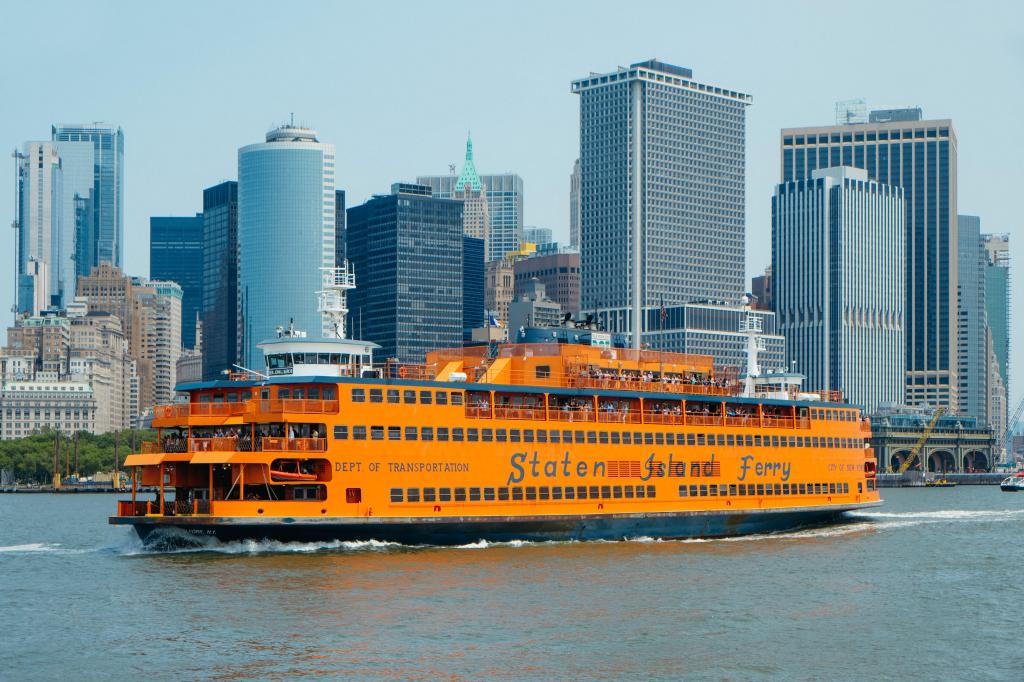 The Staten Island Ferry travels across the water with the New York City skyline in the background.