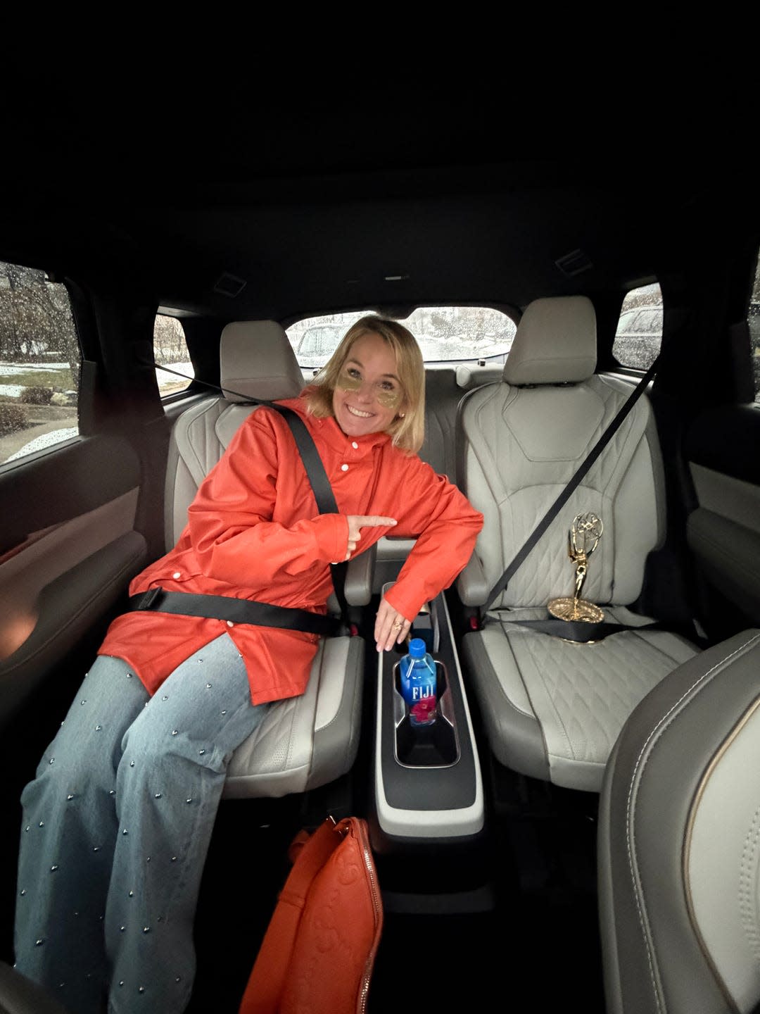 person in a car interior highlighting a water bottle and an award