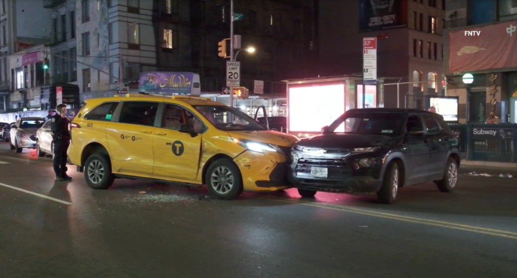 A crashed yellow taxi cab and a black unmarked police car in the street at night.