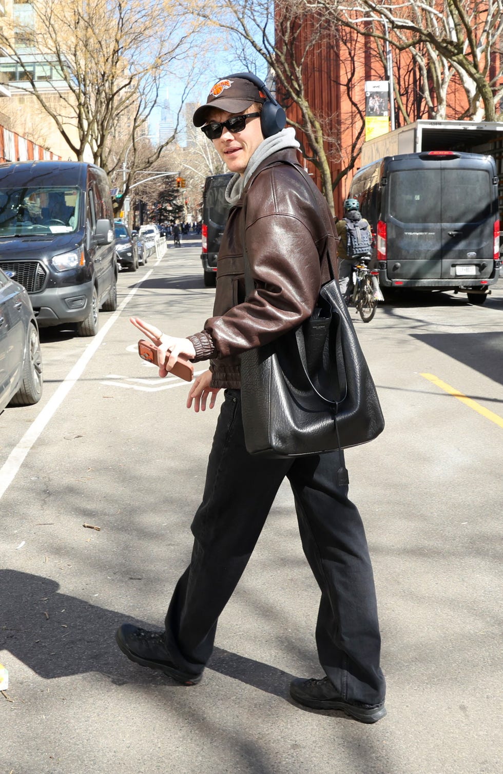 person walking on a city street with a bag and phone in hand