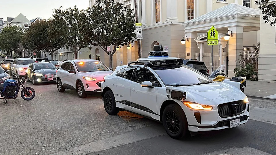 A Waymo taxi parked in front of a line of cars