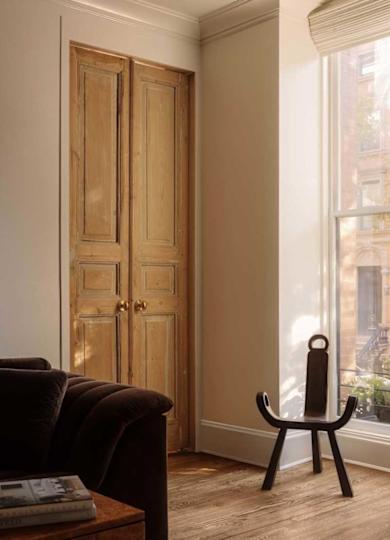 Cozy living room corner featuring a dark sofa, wooden double doors, and a unique black chair by a large window.