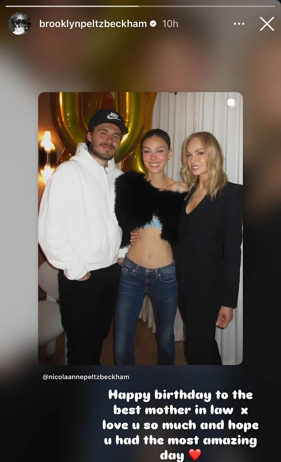 Brooklyn, Nicola, and Claudia Peltz smile together at an apparent birthday celebration for Claudia with number balloons in the background