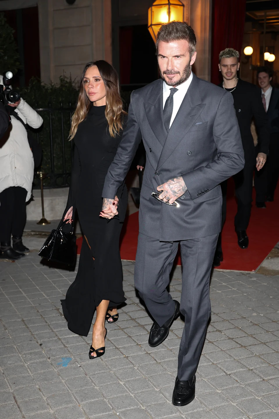Victoria and David Beckham walk hand-in-hand away from a red carpet