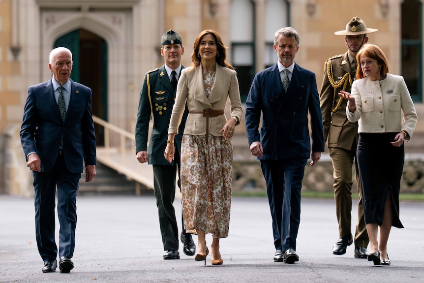 An official group walks away from historic Government House.