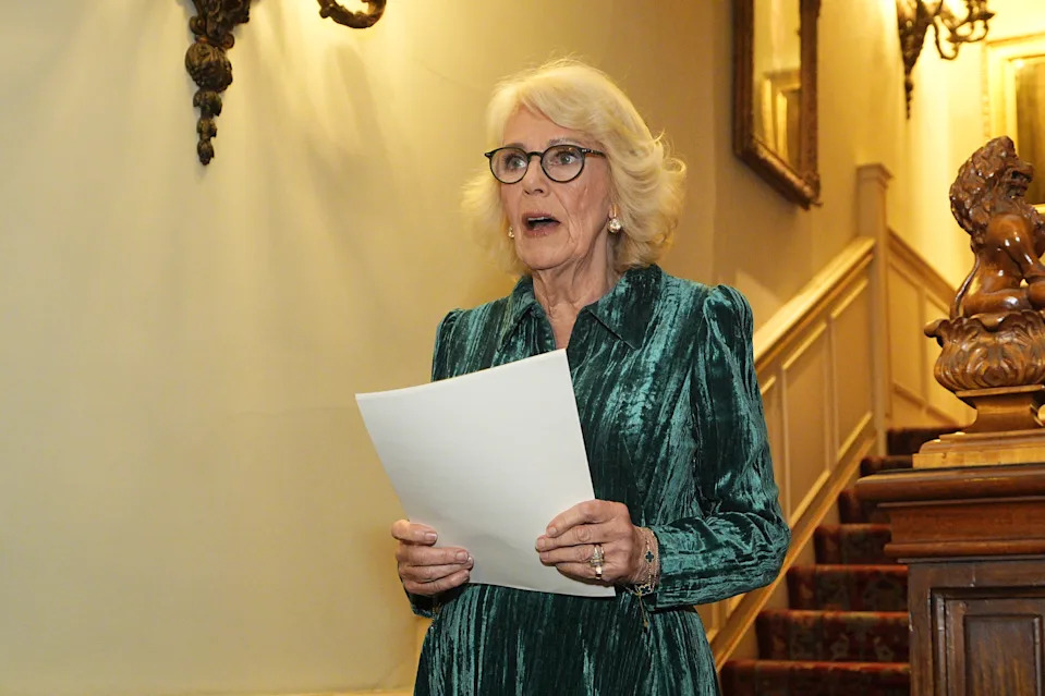 Queen Camilla wearing a green dress reading from a paper