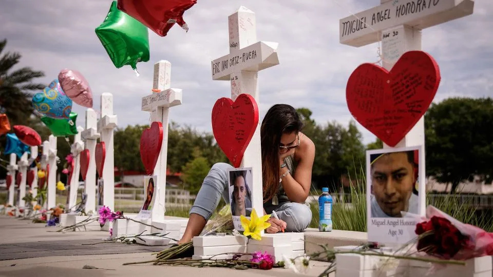A woman writes a note at a memorial with wooden crosses for each of the 49 victims of the Pulse nightclub shooting in Orlando, Florida, in June 2016. - Drew Angerer/Getty Images