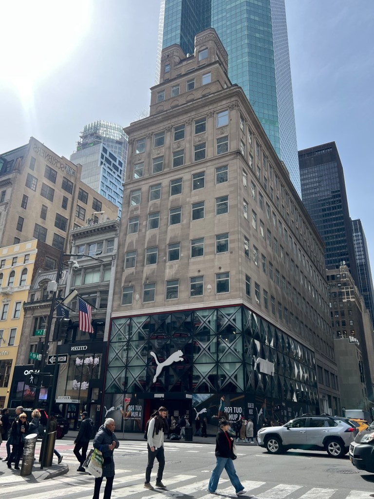 The 609 Fifth Ave building, with a Puma store on the ground floor, on a busy New York City street.